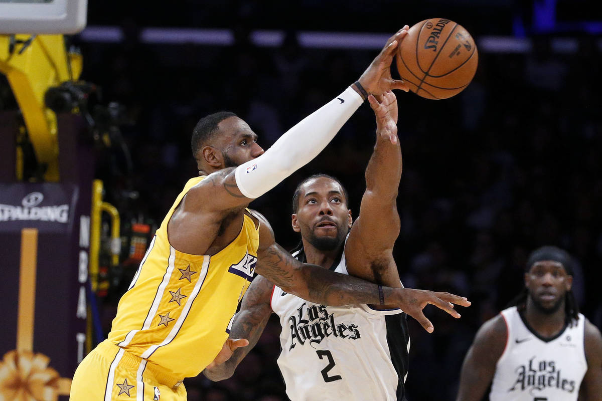 Los Angeles Lakers' LeBron James (23) and Los Angeles Clippers' Kawhi Leonard (2) reach for the ...