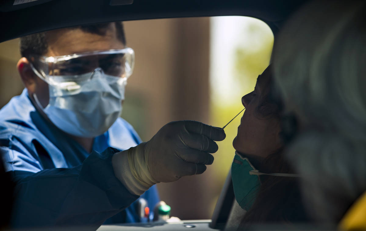 Practice Manager Jose Tirana conducts a COVID-19 test on a patient in the parking lot at Sahara ...