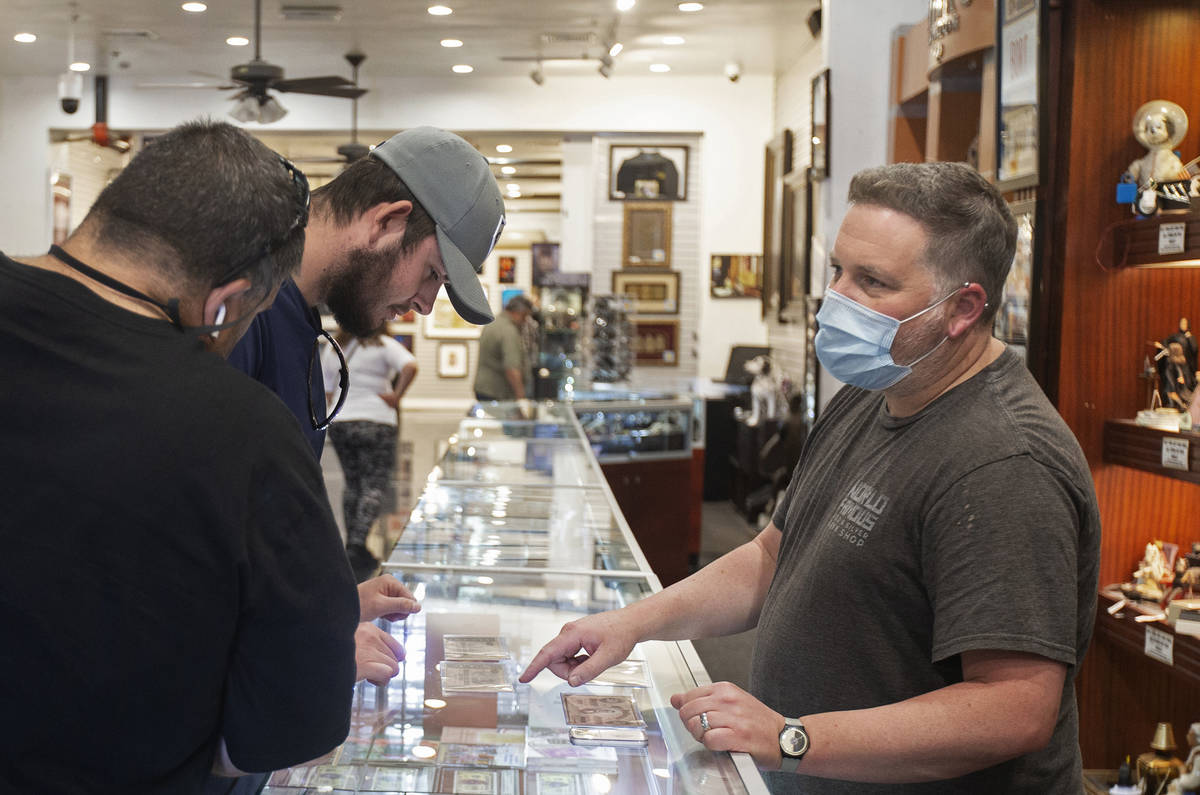 Mike Long, right, coin department manger at Gold & Silver Pawn Shop, discusses merchandise ...