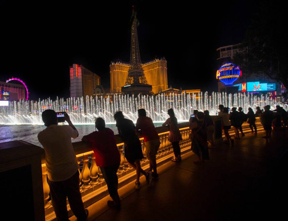 Entertainers from Mystique Showgirls watch the Fountains of Bellagio on the Strip on Wednesday, ...