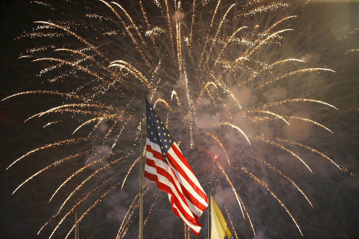 FILE - In this July 4, 2015, file photo, fireworks explode behind a United States flag during a ...