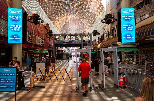 People walk through temperature scanners at the Fremont Street Experience in downtown Las Vegas ...