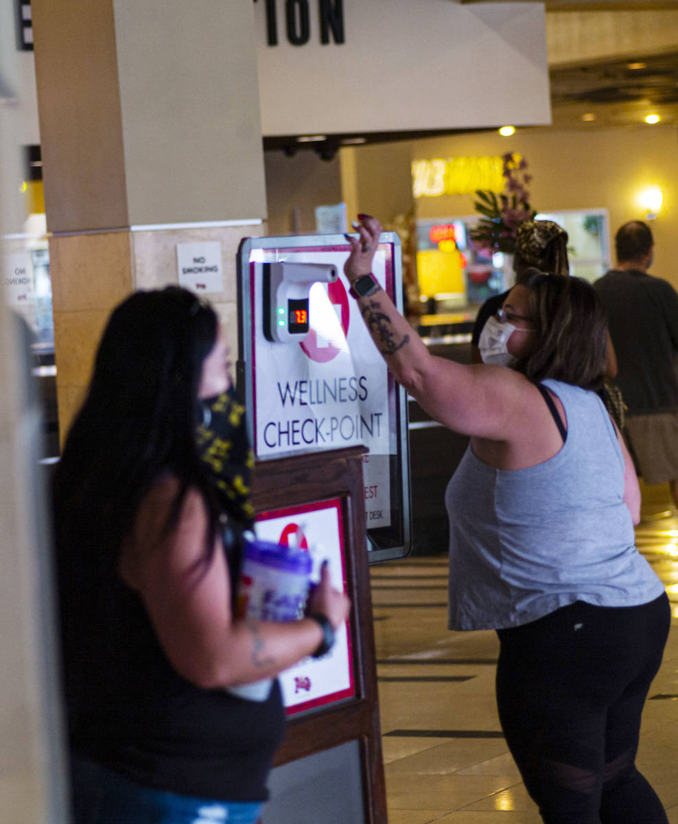 A woman holds up her wrist for a temperature check at the Golden Gate in downtown Las Vegas on ...