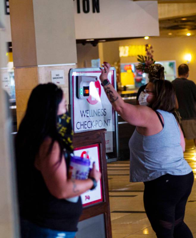 A woman holds up her wrist for a temperature check at the Golden Gate in downtown Las Vegas on ...