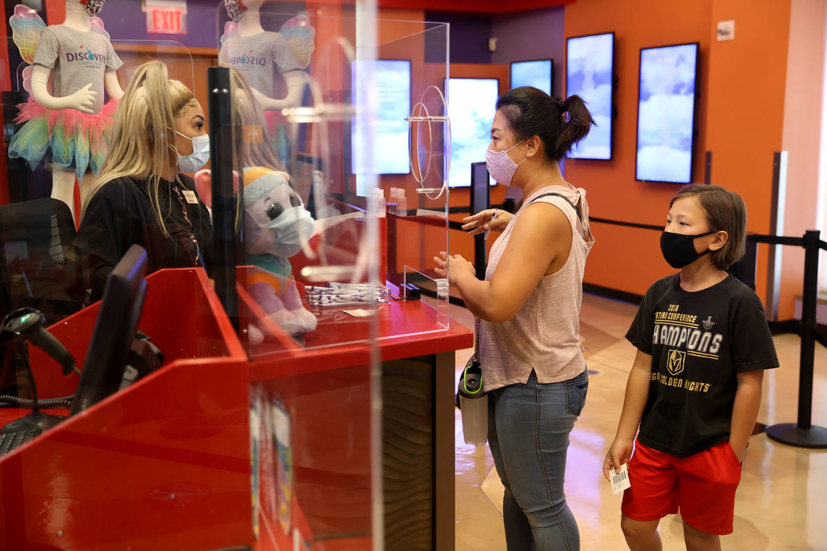 Cashier Johnetta Murdock assists Katie Cram and her son Kian, 8, of Las Vegas, at the Children' ...