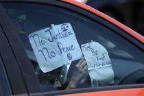 A person hangs a sign inside their car in advance of a Black Lives Matter parade from the Clark ...