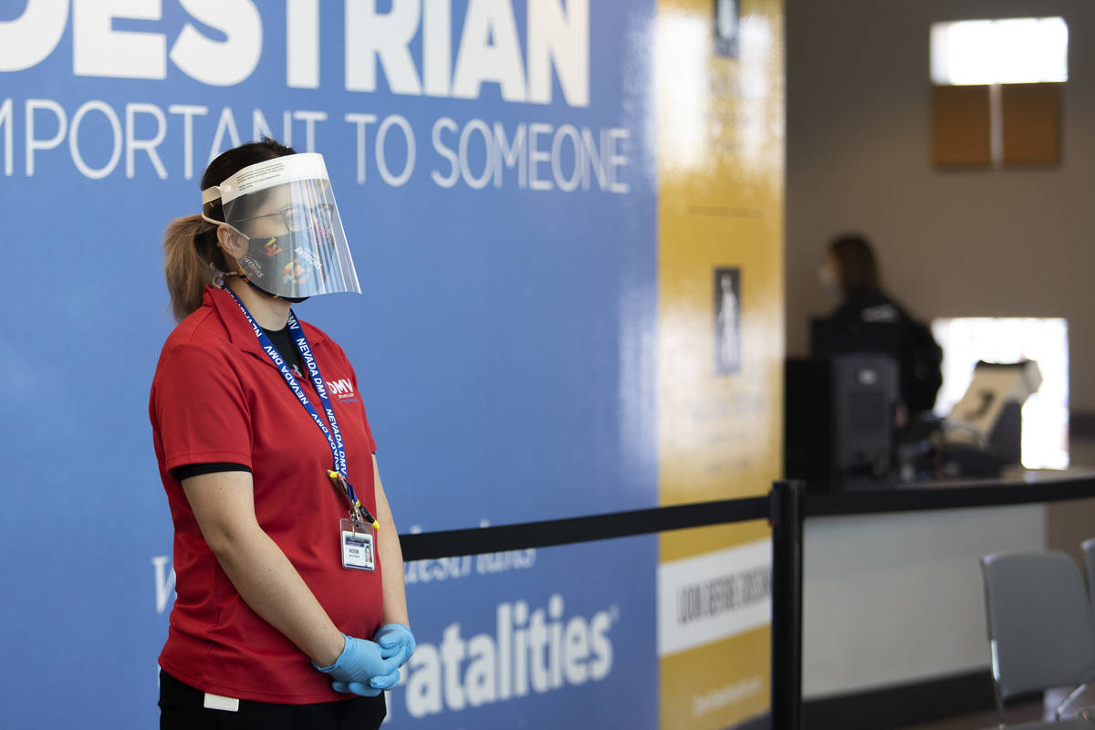 An employee wears a face shield, mask and gloves while working at the Nevada Department of Moto ...