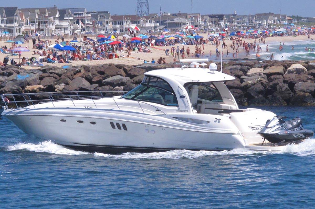 A yacht cruises through the Manasquan Inlet as a large crowd fills the beach in Manasquan, N.J. ...