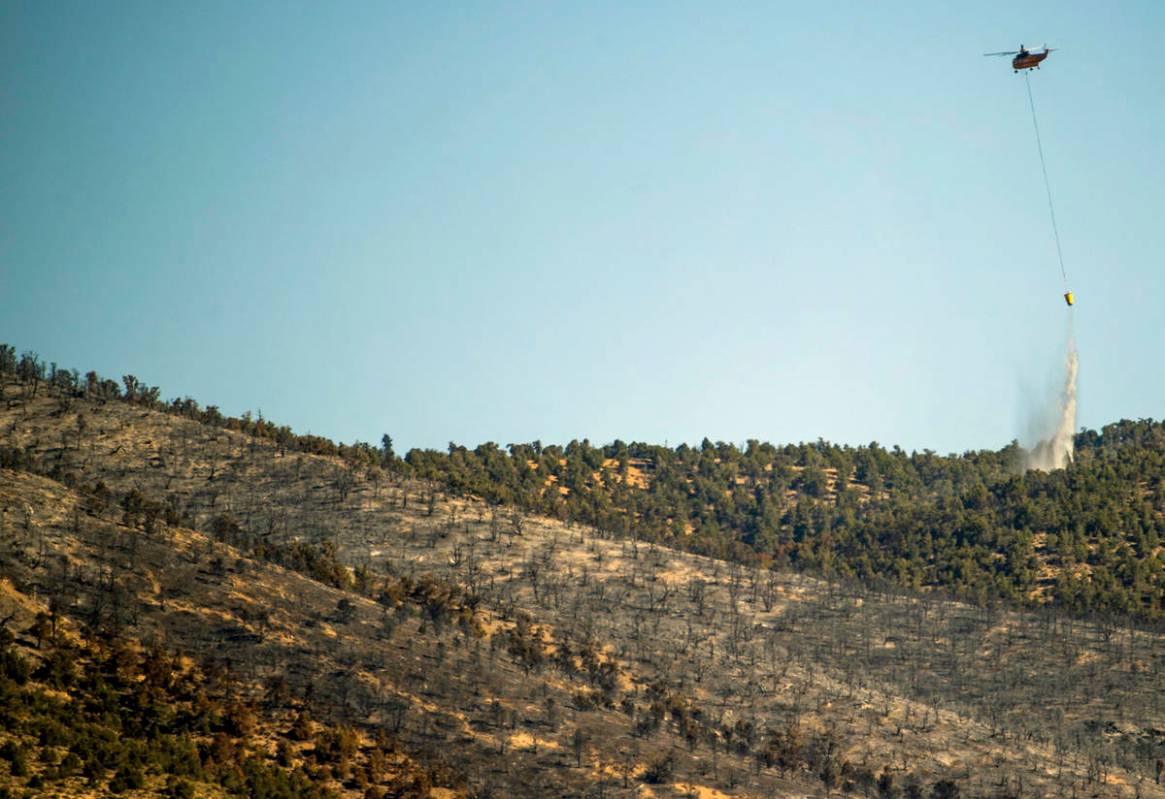 A helicopter with water bucket makes another drop over the Mahogany Fire on Mount Charleston on ...