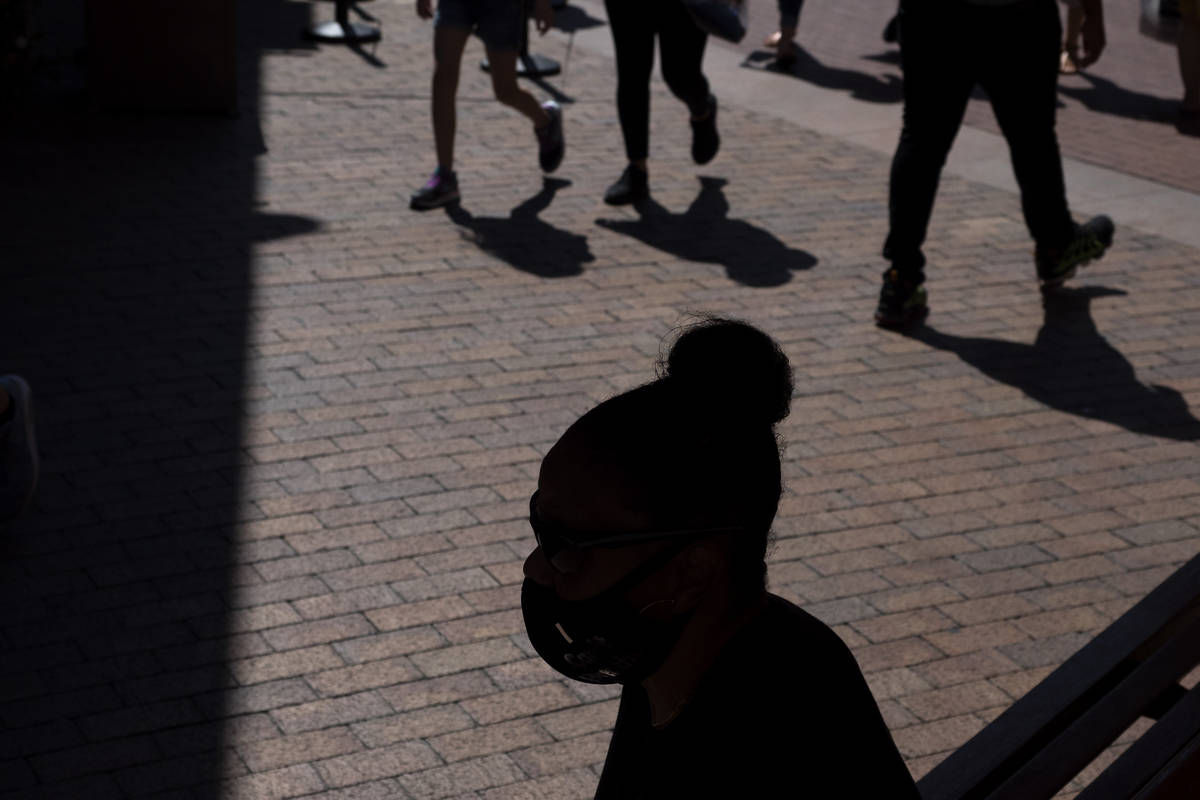 A shopper wearing a face mask sits in the shade at the Citadel Outlets in Commerce, Calif., Thu ...