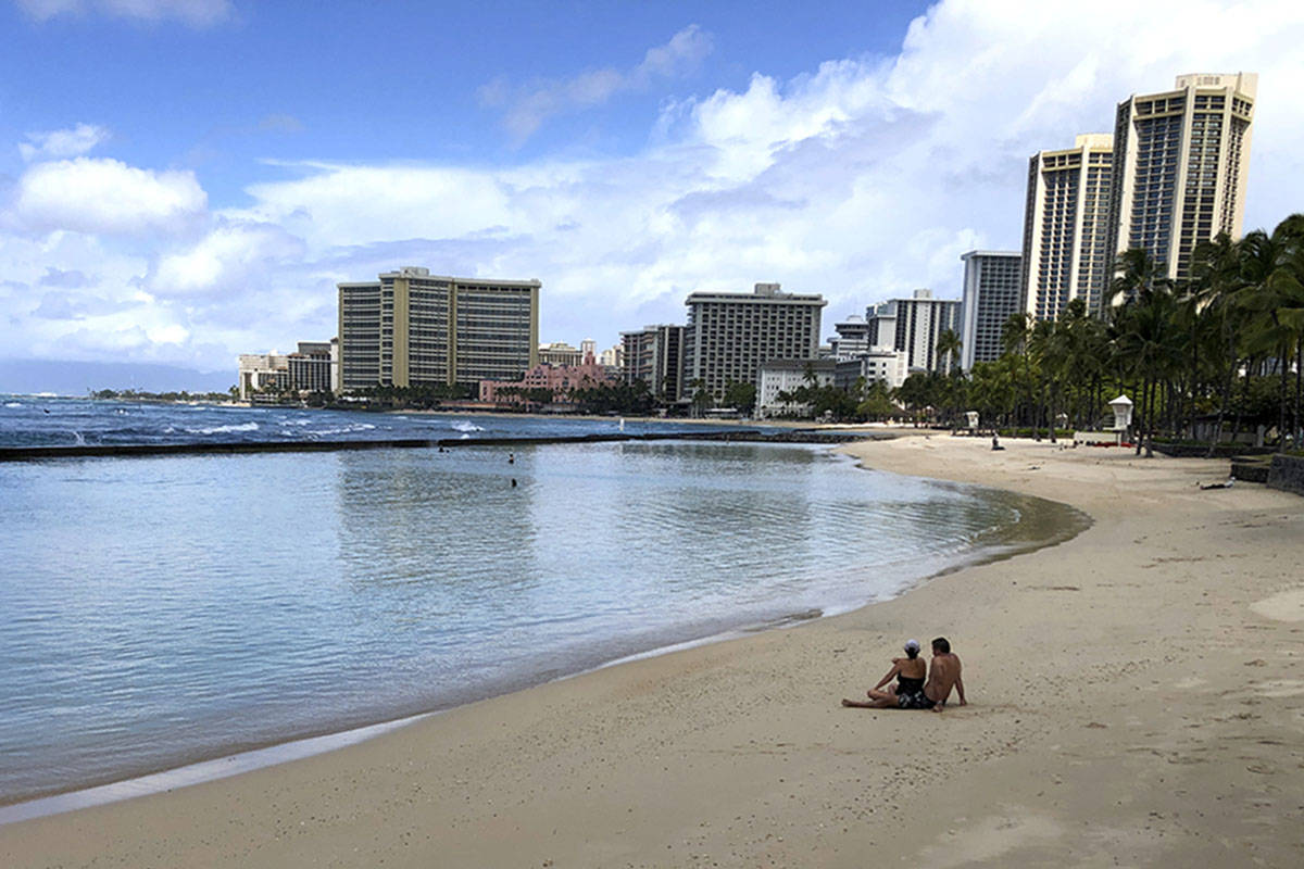 A couple rests on an empty section of Waikiki Beach in Honolulu on Saturday, March 28, 2020. (A ...