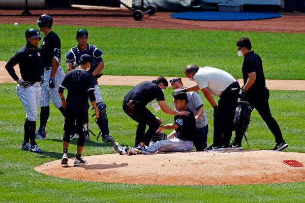 New York Yankees pitcher Masahiro Tanaka is tended to by team medical personnel after being hit ...