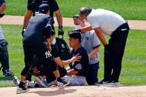 New York Yankees pitcher Masahiro Tanaka is tended to by team medical personnel after being hit ...