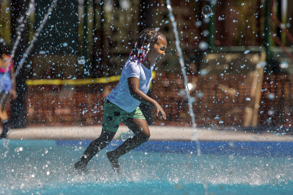 Madison Keyes, 4, runs through the fountains on a waterpad at The Paseos Park on Saturday, July ...
