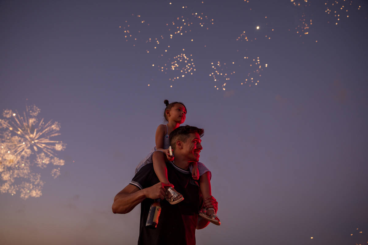 Mathew Laspina carries Arzaylea Laspina, 5, of Las Vegas, as they watch fireworks near Moapa Pa ...