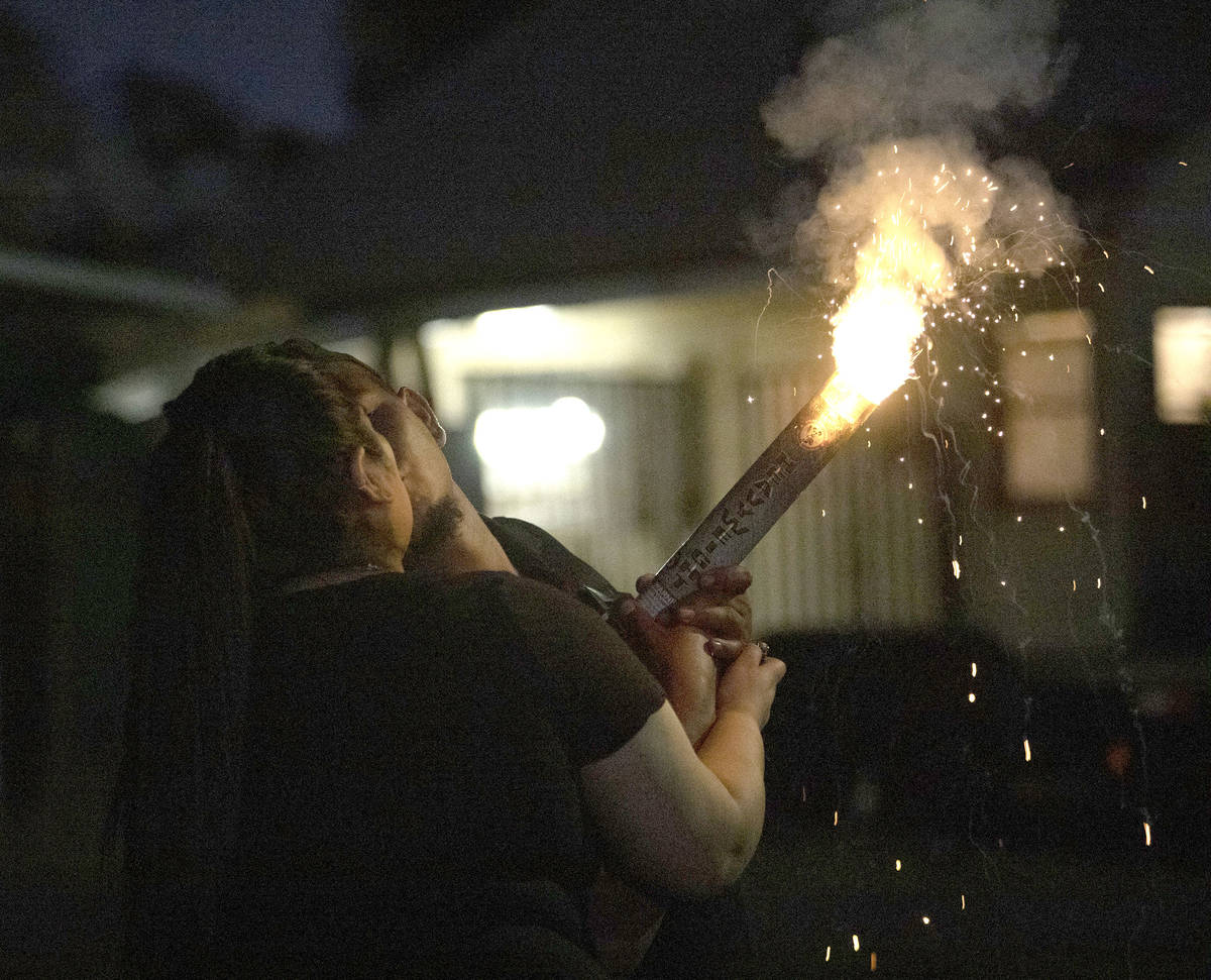 A couple shares a kiss as they light a firework to celebrate Independence Day on Saturday, July ...