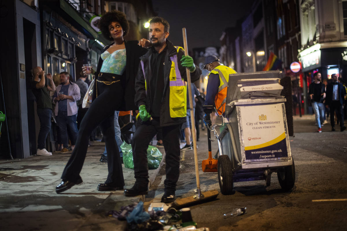 A woman poses with a street cleaner in Soho as late-night drinkers continue into the early hour ...