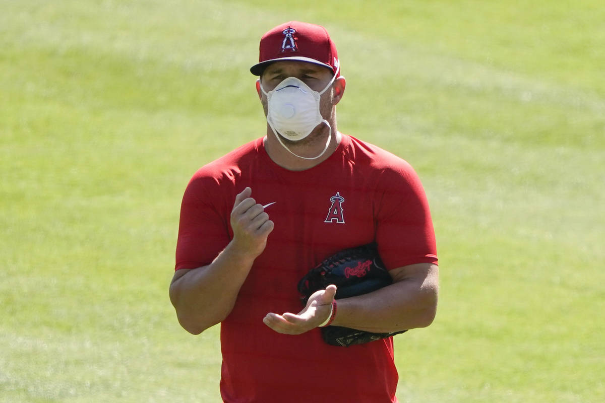 Los Angeles Angels center fielder Mike Trout (27) stands on the field wearing a face mask durin ...