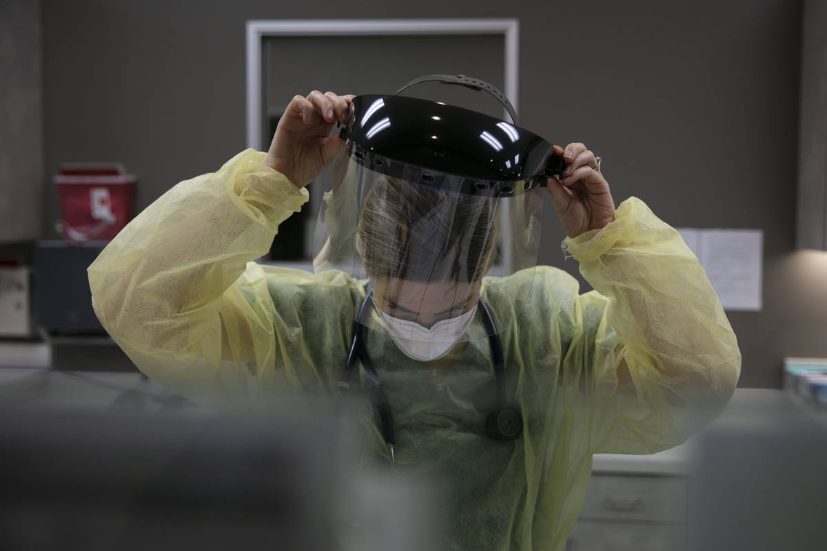 FILE - In this June 25, 2020, file photo, a physician assistant takes off her face shield after ...