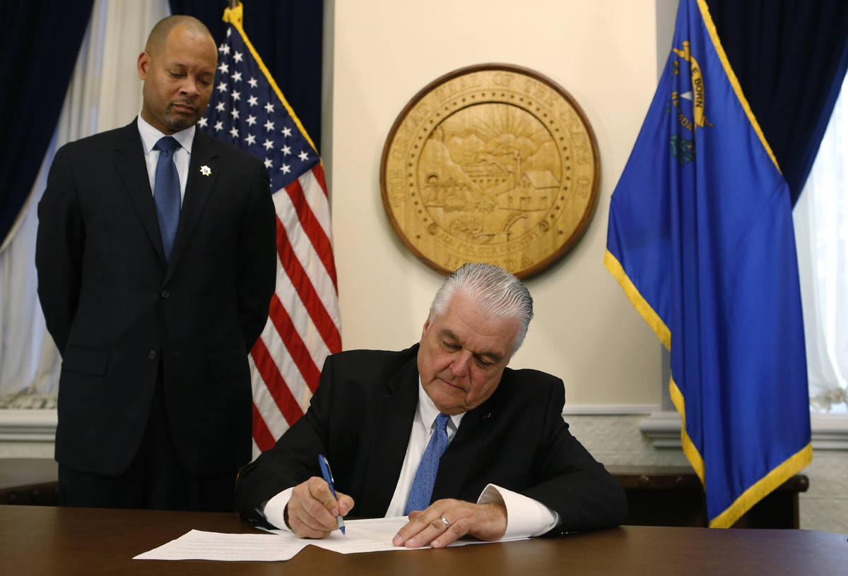 With newly sworn Attorney General Aaron Ford at his side, Nevada Gov. Steve Sisolak signs his f ...