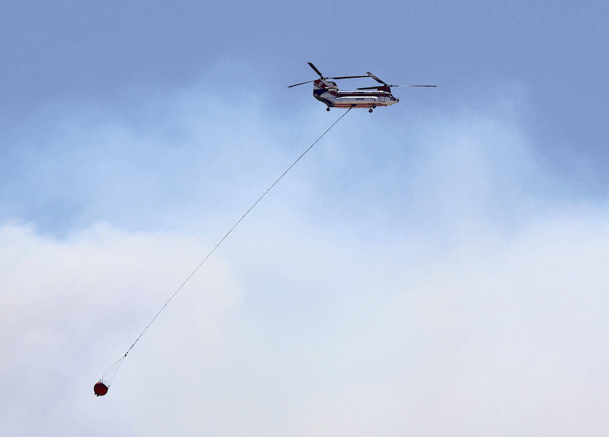 A large firefighting helicopter carries water on on its way to contain the Numbers Fire burning ...