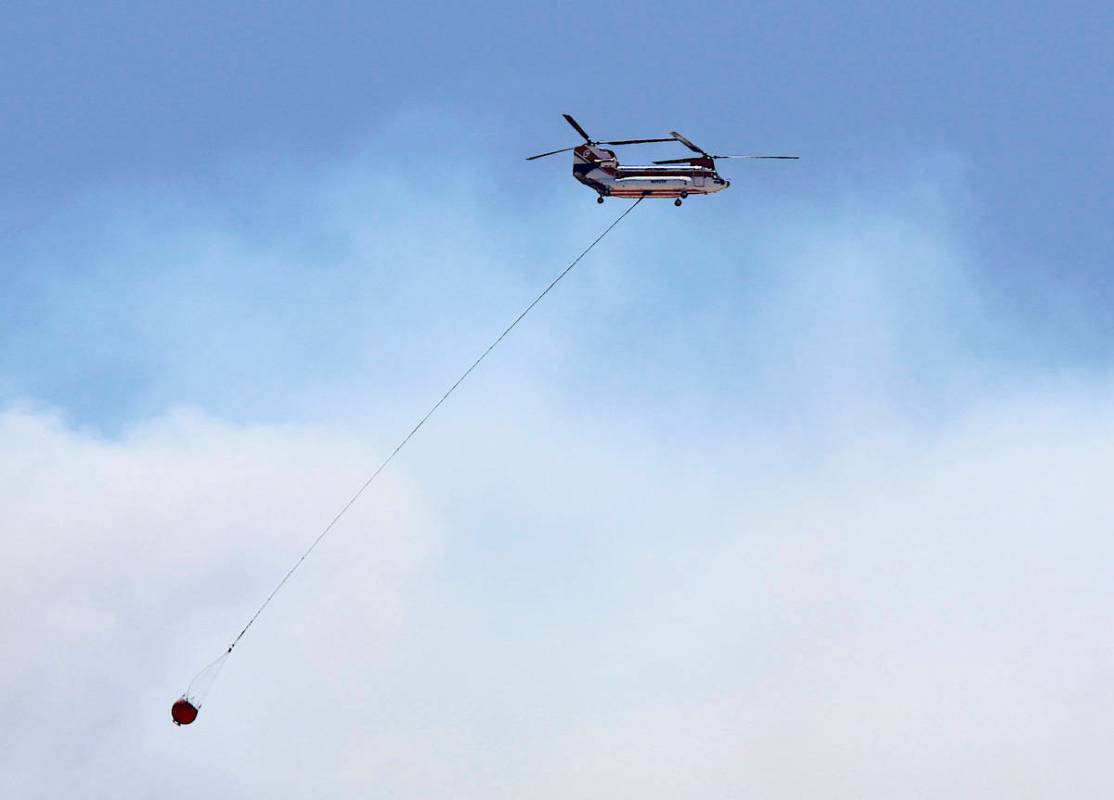 A large firefighting helicopter carries water on on its way to contain the Numbers Fire burning ...