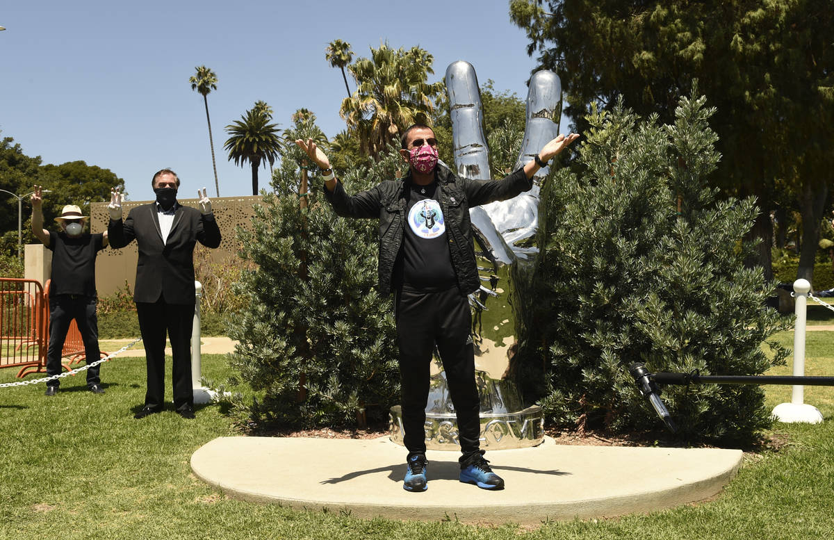 Musician Ringo Starr poses in front of his "Peace and Love" sculpture on his 80th bir ...