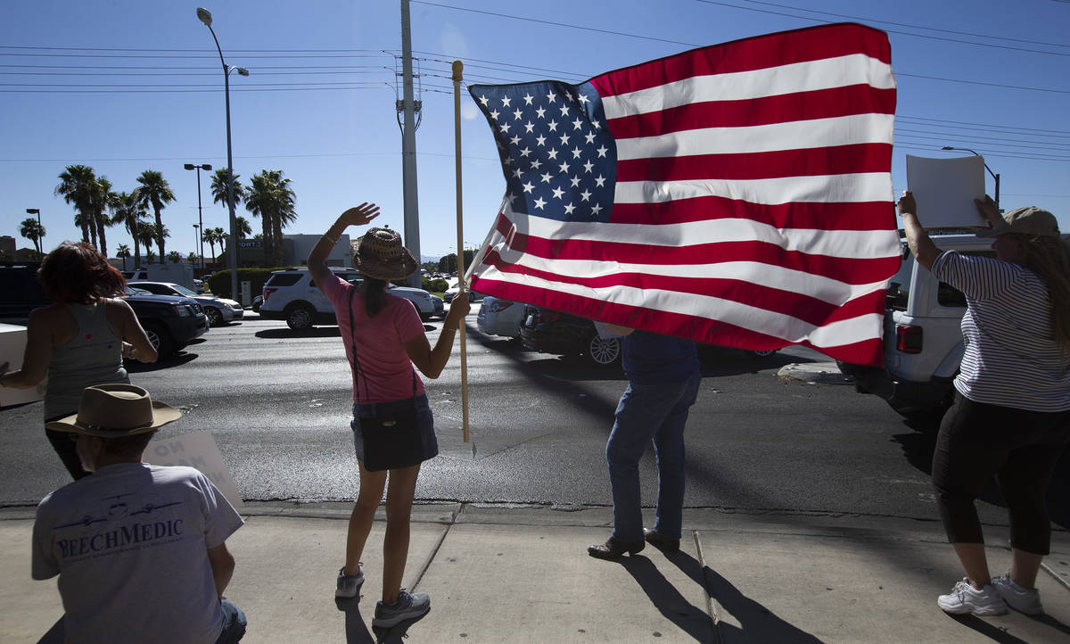 Faith Muello, second from left, holds an American Flag at the "No Mask Protest" at th ...