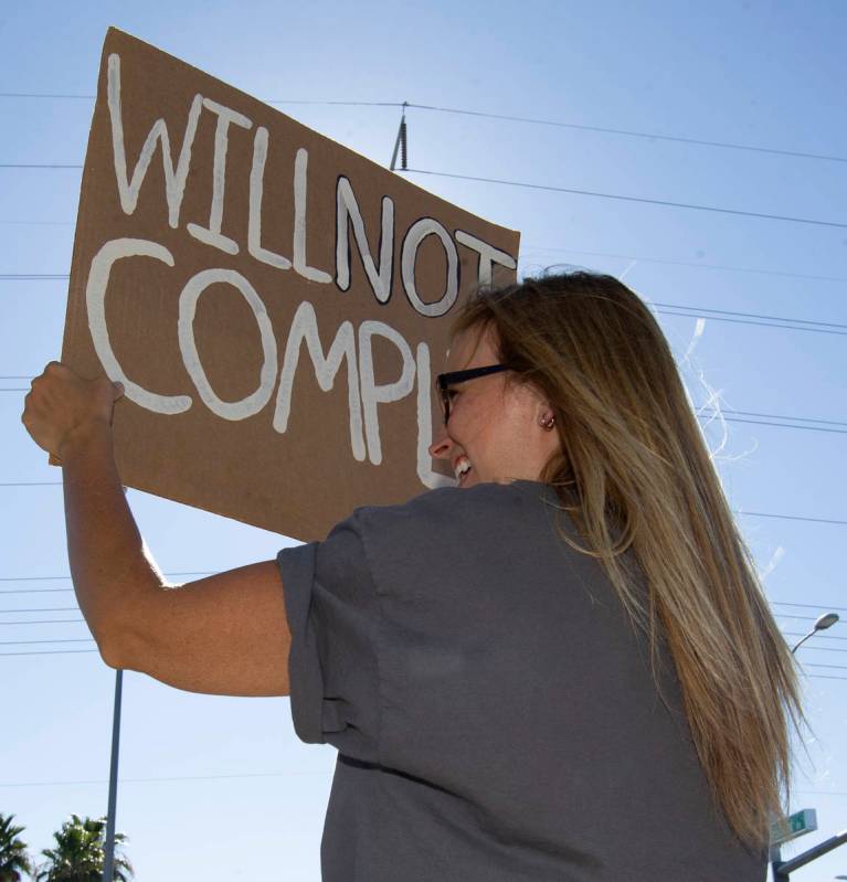 Anji Gardiner holds up a sign reading "will not comply" during the "No Mask Prot ...