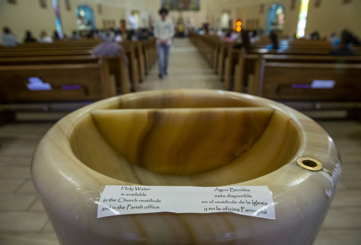 Notes in English and Spanish read that there is no holy water in the font currently for Sunday ...