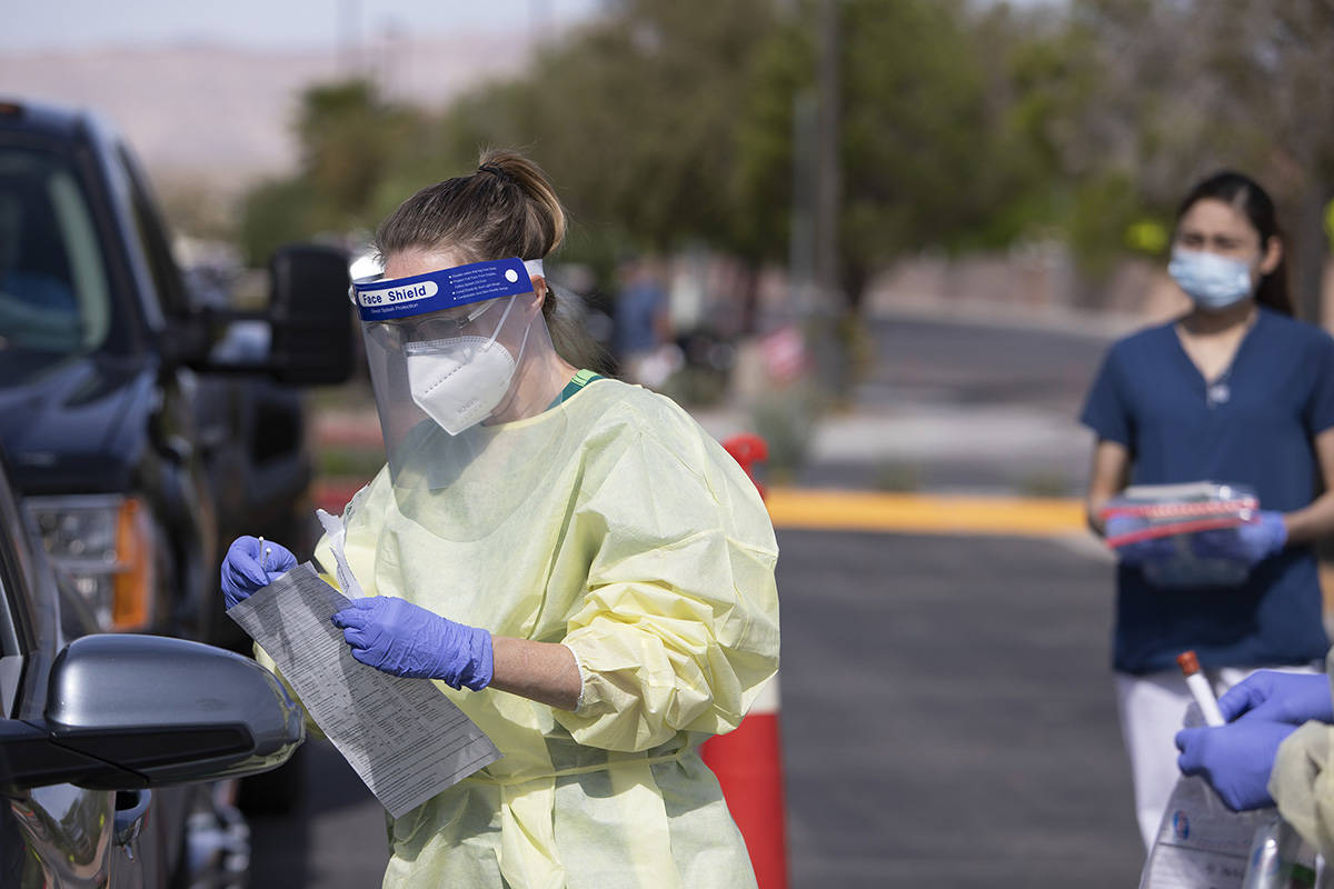 A volunteer prepares to swab a patient's nose as part of the test for COVID-19 at Calvary Chape ...