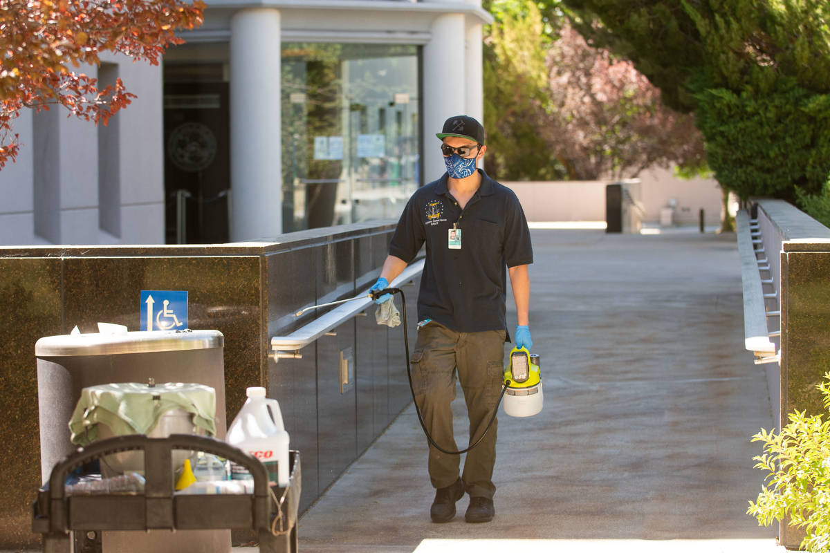 A member of the Legislatures janitorial staff cleans a hadnt railing outside the building on th ...