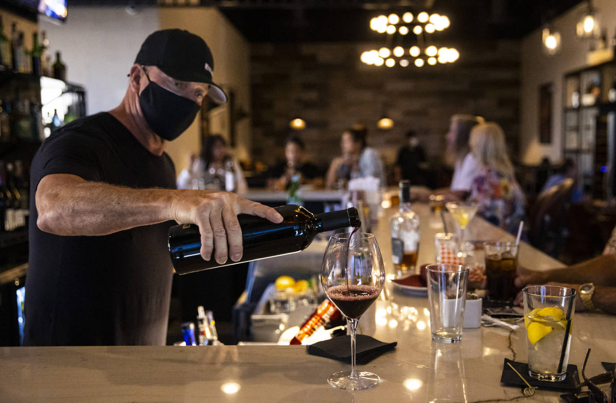 Bar manager David Cooper pours a glass of wine for Marti Taylor, not pictured, during happy hou ...