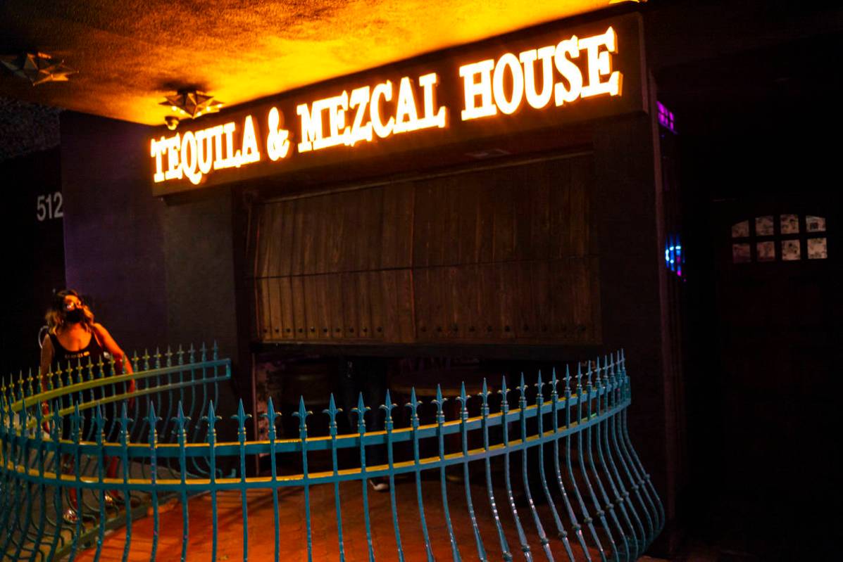 Employees lower the gate at Lucky Day Tequila and & Mezcal House on Fremont Street in downt ...