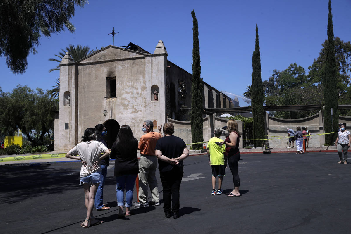 Curious onlookers stand outside the San Gabriel Mission in the aftermath of a morning fire, Sat ...