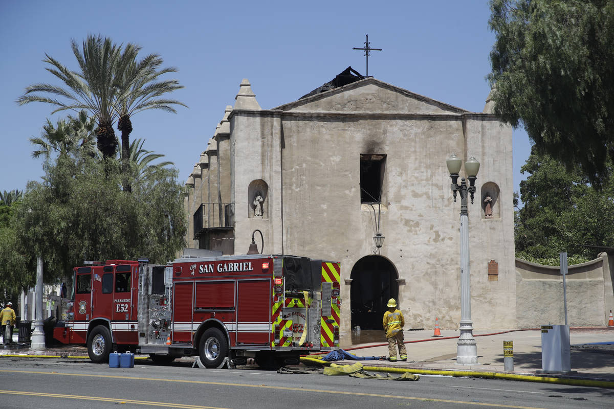 A firefighter stands outside the San Gabriel Mission in the aftermath of a fire, Saturday, July ...