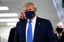 President Donald Trump wears a mask as he walks down the hallway during his visit to Walter Ree ...