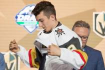 Peyton Krebs puts on a Vegas Golden Knights jersey during the first round of the NHL hockey dra ...