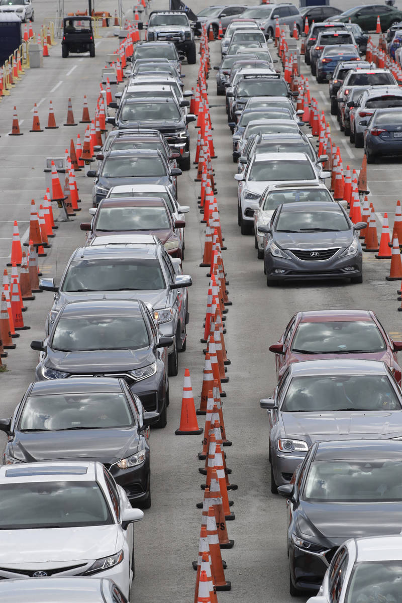 FILE - Cars wait in line at a drive-through COVID-19 testing site outside Hard Rock Stadium, in ...