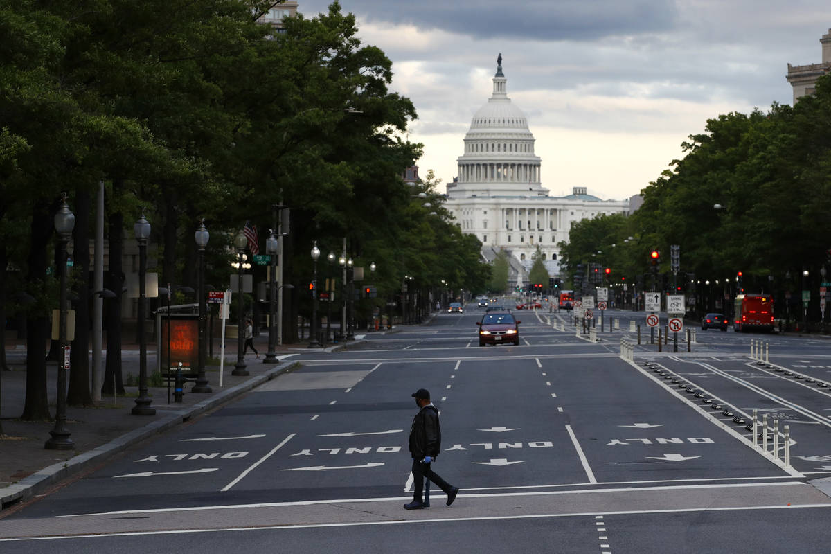 FILE - In this May 6, 2020, file photo a man walks across Pennsylvania Avenue Northwest in Wash ...