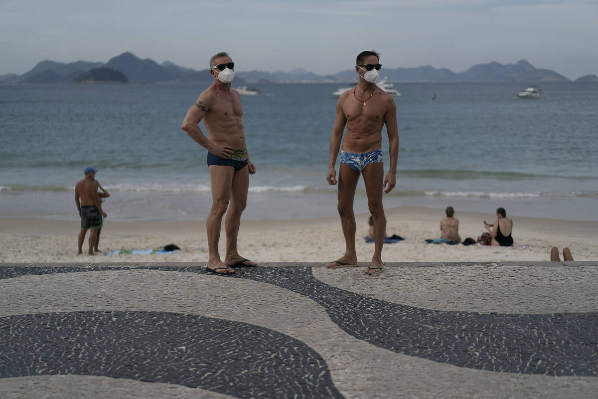 Jesus Costa and Antonio Ancon, right, stand on Copacabana beach amid the outbreak of the new co ...