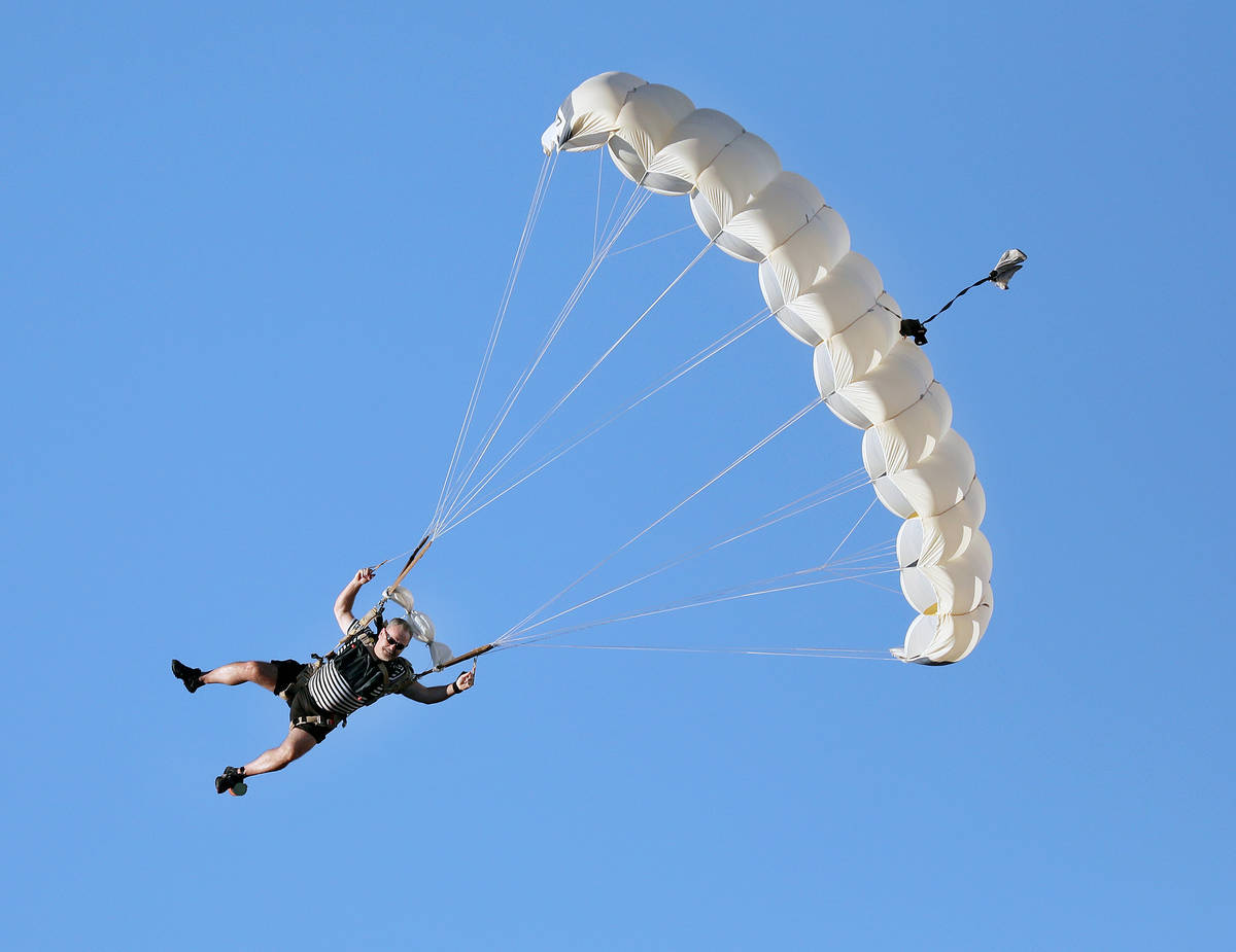 A skydiver descends from a plane for Marché Bacchus' Bastille Day celebration, in front of the ...