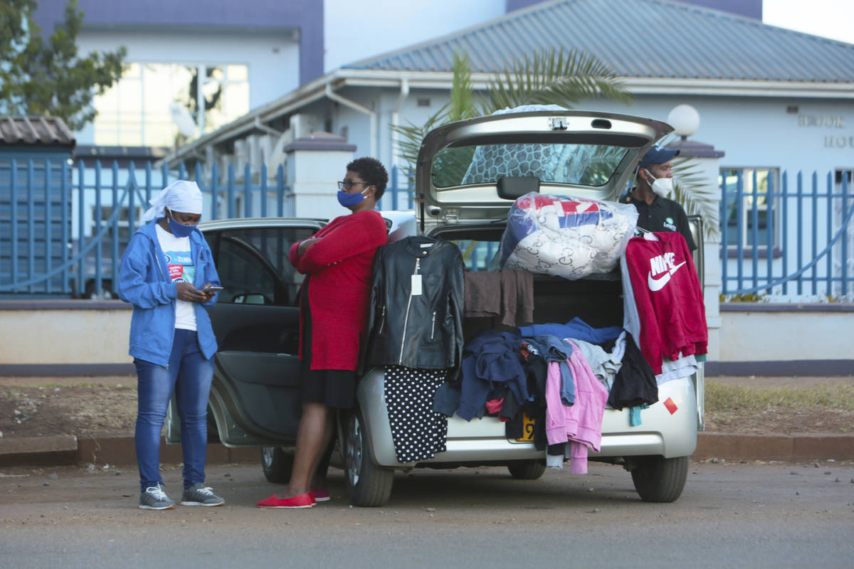 People sell clothes displayed on their car by the side of a busy road in Harare, Zimbabwe, Tues ...