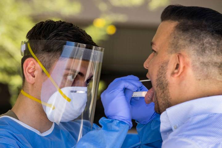 Nevada National Guard soldier PFC Nikolas Herrera, left, inserts a swab into the mouth of Paulo ...