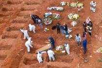Cemetery workers in protective clothing bury victims of the new coronavirus at the Vila Formosa ...