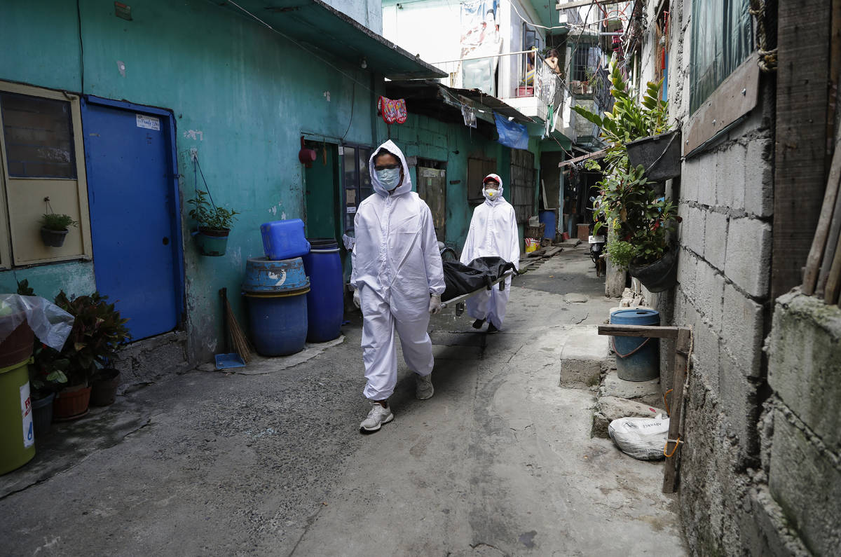 Funeral home workers in protective suits carry a body during the start of a lockdown due to a r ...