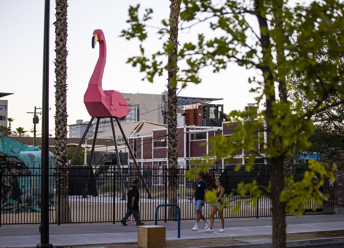 People walk by Phoenicopterus Rex, a giant replica of a pink plastic lawn flamingo standing 40 ...
