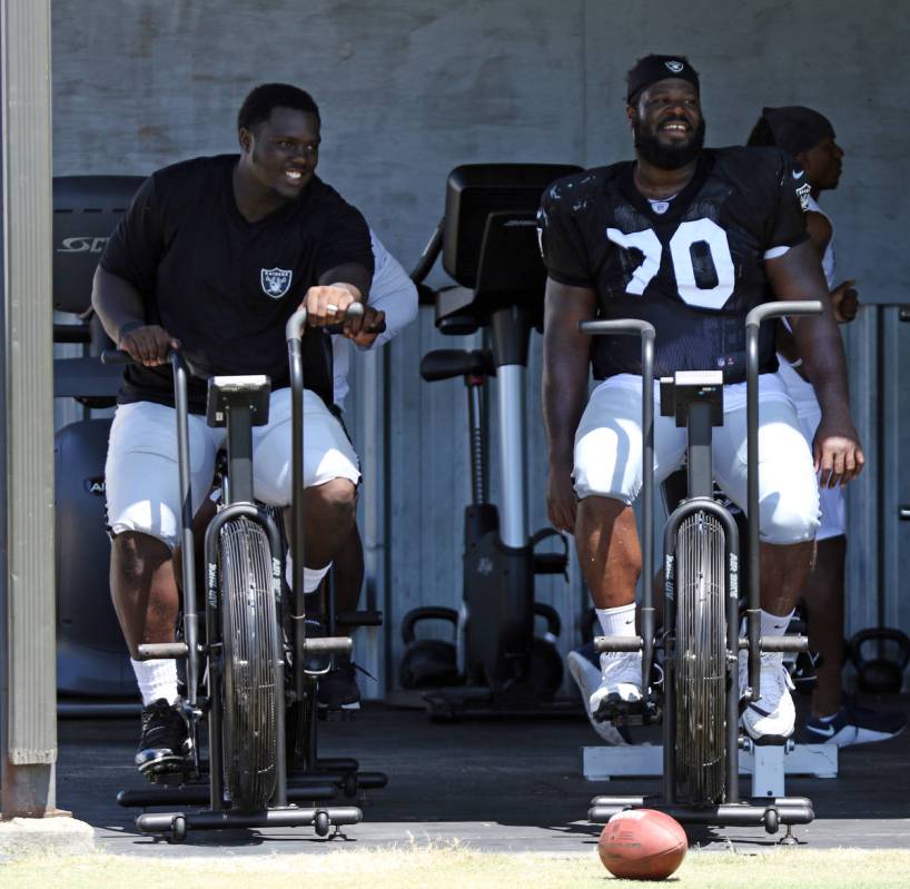 Oakland Raiders offensive guards Lester Cotton, left, and Jonathan Cooper ride air bikes after ...