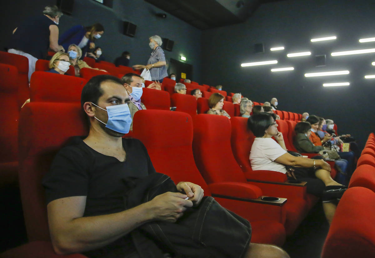 People wear protective masks as they wait for the screening of a movie in Paris, Monday, June 2 ...