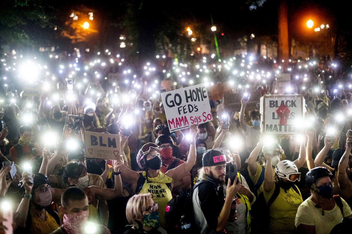 Hundreds of Black Lives Matter protesters hold their phones aloft on Monday, July 20, 2020, in ...